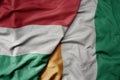 big waving national colorful flag of cote divoire and national flag of hungary