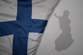 big waving national colorful flag and map of finland on the gray background Royalty Free Stock Photo