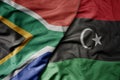 big waving national colorful flag of south africa and national flag of libya
