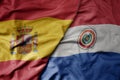big waving national colorful flag of spain and national flag of paraguay