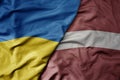big waving national colorful flag of ukraine and national flag of latvia
