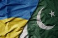 big waving national colorful flag of ukraine and national flag of pakistan
