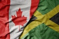 big waving realistic national colorful flag of canada and national flag of jamaica Royalty Free Stock Photo