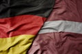 big waving realistic national colorful flag of germany and national flag of latvia