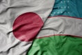 big waving realistic national colorful flag of japan and national flag of uzbekistan