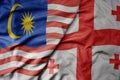 big waving realistic national colorful flag of malaysia and national flag of georgia
