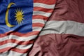 big waving realistic national colorful flag of malaysia and national flag of latvia