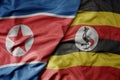 big waving realistic national colorful flag of north korea and national flag of uganda
