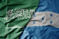 big waving realistic national colorful flag of saudi arabia and national flag of honduras