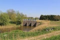 A big concrete weir barrage in a natural creek in the dutch countryside in springtime