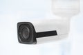 Big white professional surveillance camera. CCTV mounted on ceiling. Security system concept. Copyspace, neutral light blue ba