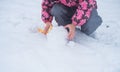 Big white snow comp. Baby pens touch cold snow. The child plays outdoors with snow in March