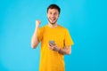 Excited man using smartphone at studio, celebrating online win Royalty Free Stock Photo