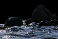 Big windy waves splashing over rocks. Wave splash in the lake isolated on black background. Waves breaking on a stony beach Royalty Free Stock Photo