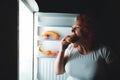 Big woman eat fast food. Red hair fat girl looking inside refrigerator with burger. Unhealthy and healthy food concept with plus Royalty Free Stock Photo