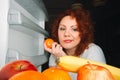 Big woman eat fruit. Red hair fat girl looking inside refrigerator. Unhealthy and healthy food concept with plus size female on k