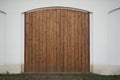 Big wooden barn gate. Monumental farm door, two timber leaf, closed brown gateway with planks and nails