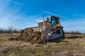 A big yellow bulldozer pushes the ground and makes a new road