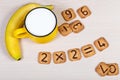 Big yellow cup of milk, banana and funny cookies with numbers on light wooden background. Healthy breakfast for a child. Royalty Free Stock Photo