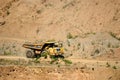 Big yellow dump truck transporting stone and gravel in an sand open-pit.