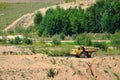 Big yellow dump truck transporting stone and gravel in an sand open-pit.