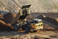 Big yellow dump truck working in an sand open-pit.