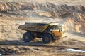 Big yellow dump truck works in an sand open-pit