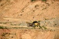 Big yellow dump truck works in an sand open-pit.