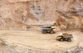 Big yellow dump trucks working in the open-pit.