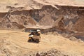 Big yellow dump trucks working in the open-pit.