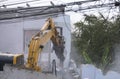 Big yellow excavator removal home building by destroy concrete wall. uproot old construction house for development new project