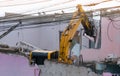 Big yellow excavator removal home building by destroy pink concrete wall. uproot old construction house for development new