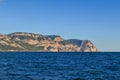 Big yellow green stone mountain with cliffs on horizon, Black sea in bright sun light, blue sky, view from water Royalty Free Stock Photo