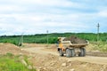 Big yellow mining truck working in the limestone open-pit. Loading and transportation of minerals in the dolomite mining quarry.