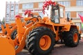 Big yellow orange tractor with bucket and big red bows on the roof