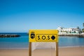 Big yellow Sos emergency sign in empty spanish beach on a sunny summer day with nobody on the beach