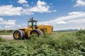 Big yellow tractor on sunflower and corn field blue cloudy sky Royalty Free Stock Photo