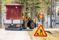 Big yellow tractor turn right while relocates old small red woden house in the trailer, sunny summer day, nearby to Umea city,