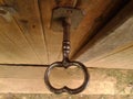 Bigger old worn black shiny key in oak wooden dusty cellar door, close-up from above, in daylight