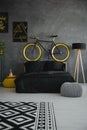 Bike above black bed in modern grey bedroom interior with patter Royalty Free Stock Photo