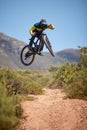 Bike, bmx and fitness with a man biker on a dirt trail or track taking a jump with a mountain bike. Sky, nature and Royalty Free Stock Photo