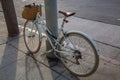 A bike with a carrier tied to a pole on a sidewalk