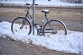 Bike chained to a pole on a city street in winter