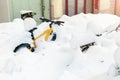 Bike covered with big thick snow layer after blizzard at european city street in winter. Abandoned bicycle buried in snowstorm Royalty Free Stock Photo