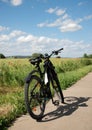 A bike, a bike with electric drive stands on a stone path next to the spring green field with red poppies. On far background, blue Royalty Free Stock Photo