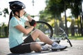 Bike injuries. Young woman cyclist fell fell off road bike while cycling. Bicycle accident, injured knee Royalty Free Stock Photo