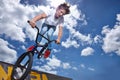 Bike, jump and teen on ramp for sport performance, ride or training for event at park with sky. Bicycle, stunt or kid Royalty Free Stock Photo