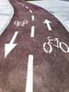 Bike lane with painted white bicycle sign or symbol and arrows on the ground for directions on new black tarmac road Royalty Free Stock Photo