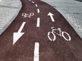 Bike lane with painted white bicycle sign or symbol and arrows on the ground for directions on new black tarmac road Royalty Free Stock Photo