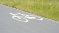 Bike lane sign on the ground, simple white bike symbol painted on the path, road, closeup detail, nobody. Cycling, biking Royalty Free Stock Photo